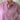 Woman wearing a pink shirt standing indoors with a blurred background