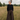 Woman standing in a field wearing a black top and brown wide-leg pants.