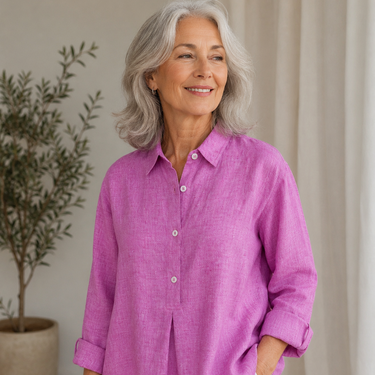 Woman wearing a pink shirt in an indoor setting with a plant in the background