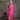 A woman with gray hair wearing a bright pink linen dress with short sleeves and a square neckline, standing next to a small black wooden stool against a textured gray studio backdrop.