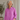 Woman wearing a pink shirt in an indoor setting with a plant in the background