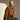 Woman in a brown outfit sitting on a stool against a gray background